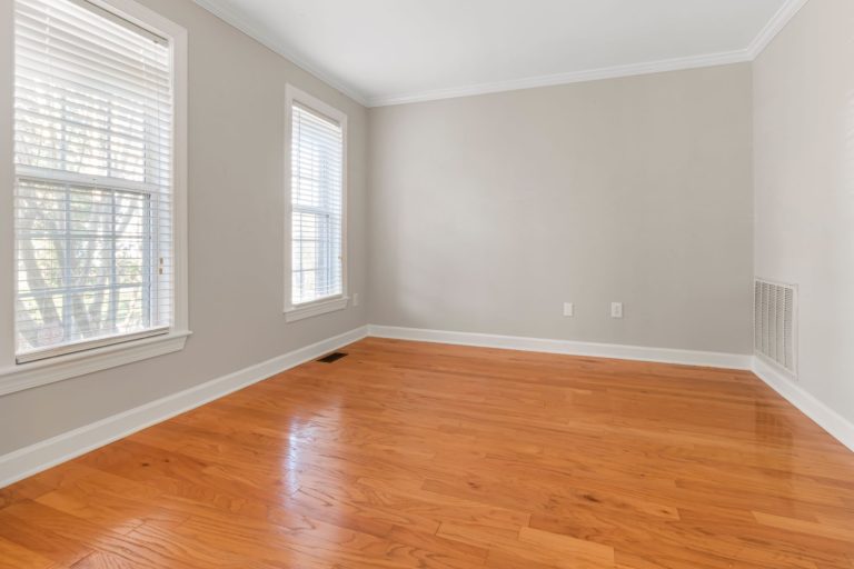 Spacious empty room with natural light, hardwood floors, and neutral walls