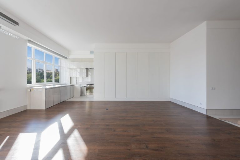 Dark-stained hardwood flooring in a bright empty Oregon room with sunlight falling across the boards from a wall of windows