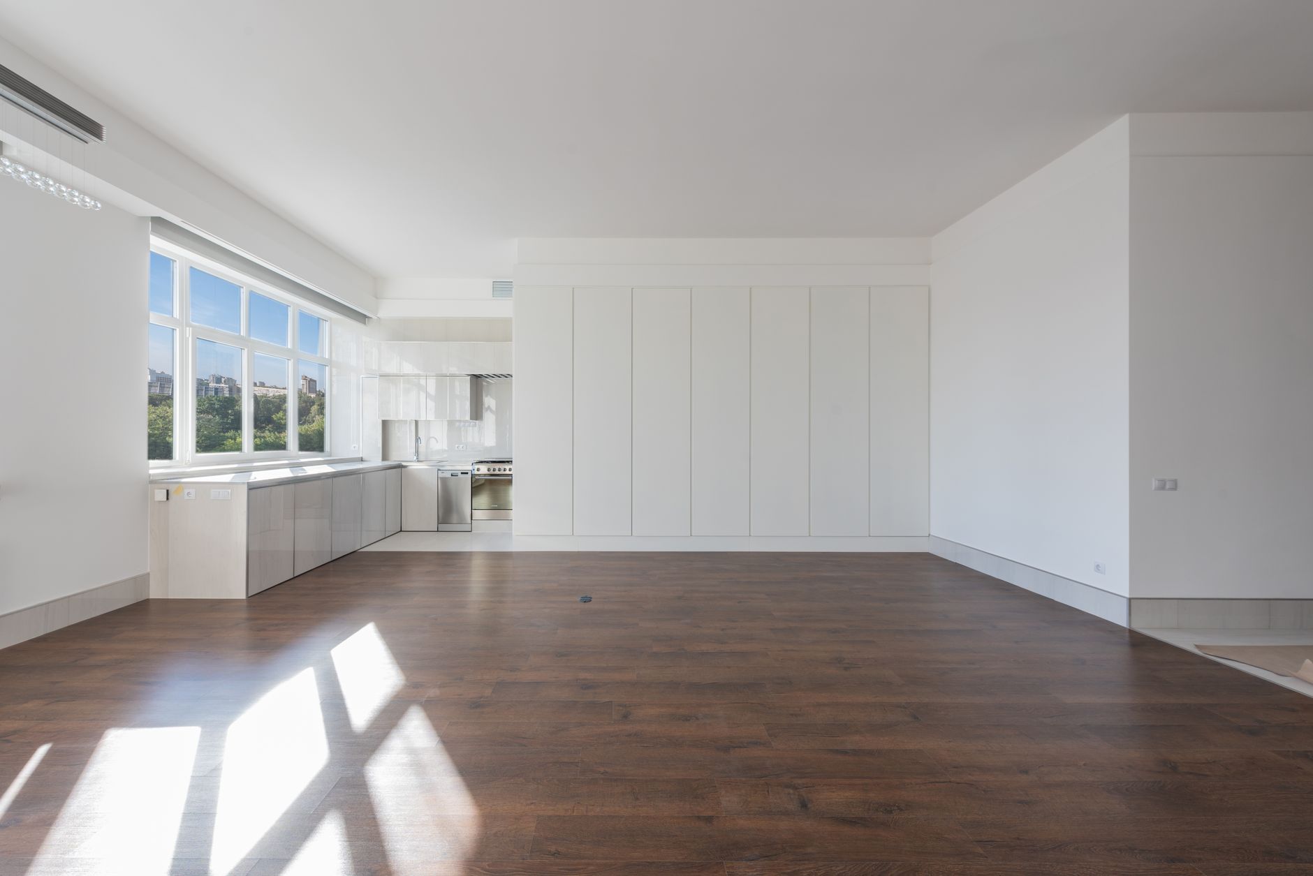 Dark-stained hardwood flooring in a bright empty Oregon room with sunlight falling across the boards from a wall of windows