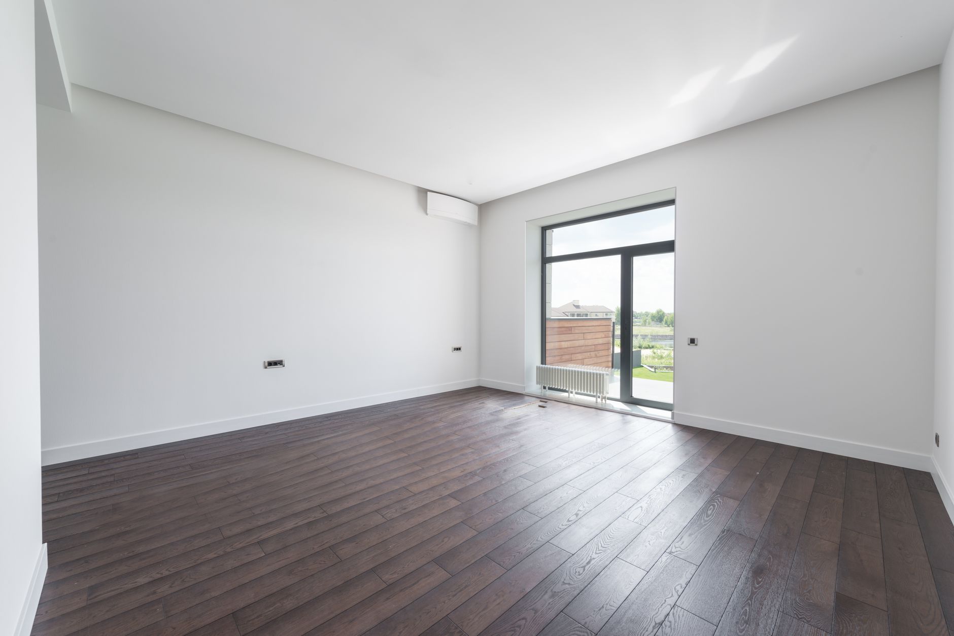 Grey-brown laminate plank flooring in an empty Oregon room with a full-height sliding door onto the garden