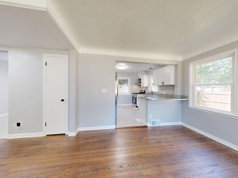 Refinished dark hardwood flooring running from an empty Oregon room through to the kitchen beyond