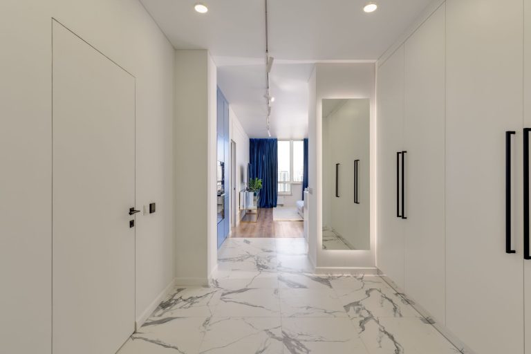 Veined white marble flooring in an Oregon hallway between fitted wardrobes, looking through to a living room