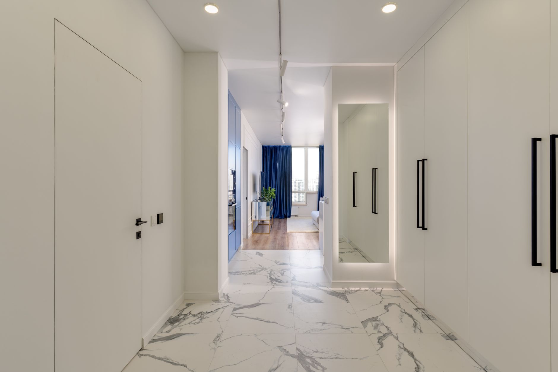 Veined white marble flooring in an Oregon hallway between fitted wardrobes, looking through to a living room