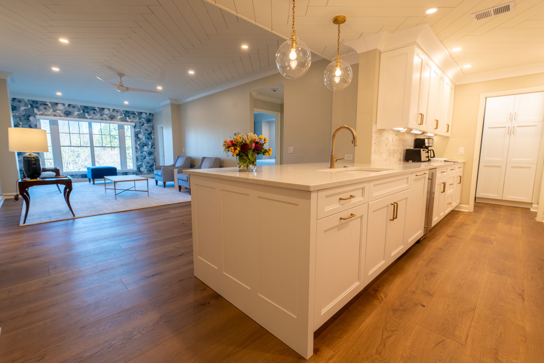 Oak hardwood flooring in an Oregon kitchen with a long island, running through to the living room beyond