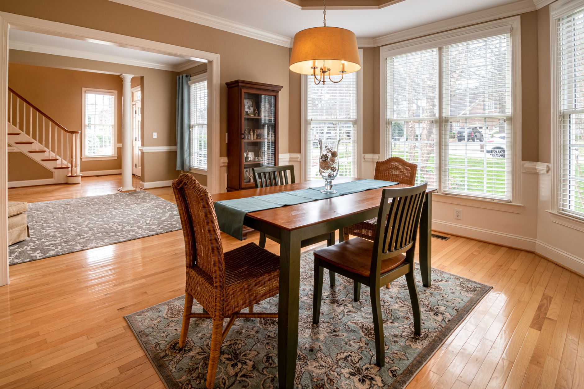 A sunlit dining room featuring a wooden table and wicker chairs, showcasing luxury interior design